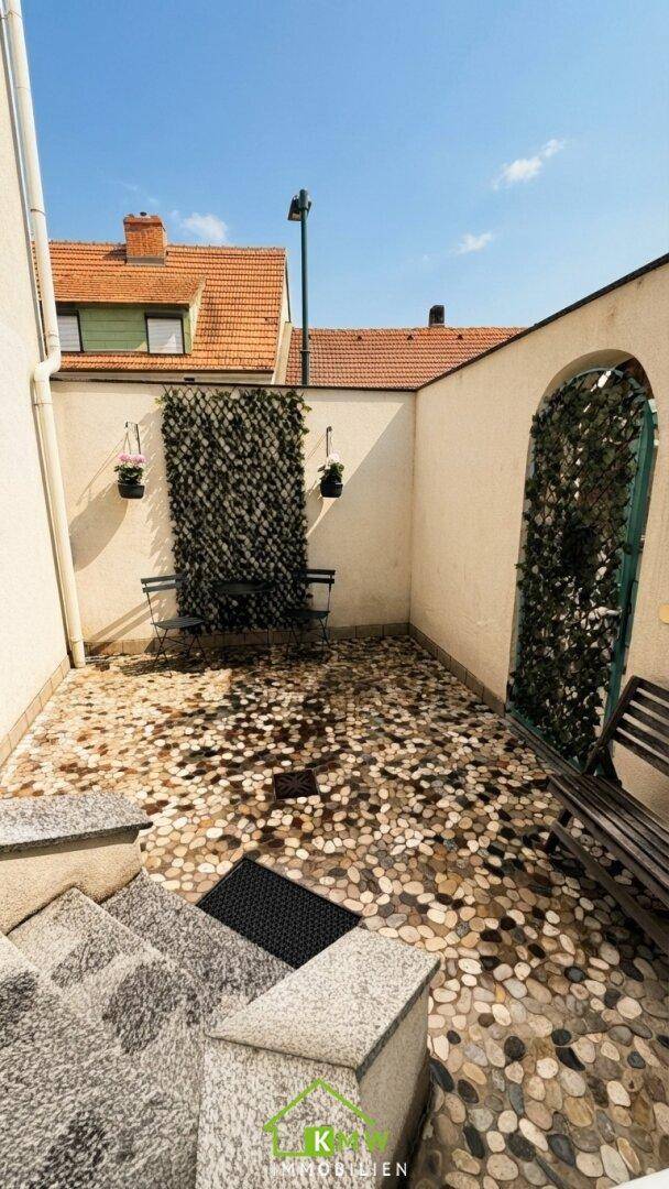Innenhof mit Kiesboden, Sitzbank und dekorativer Wandbegrünung.