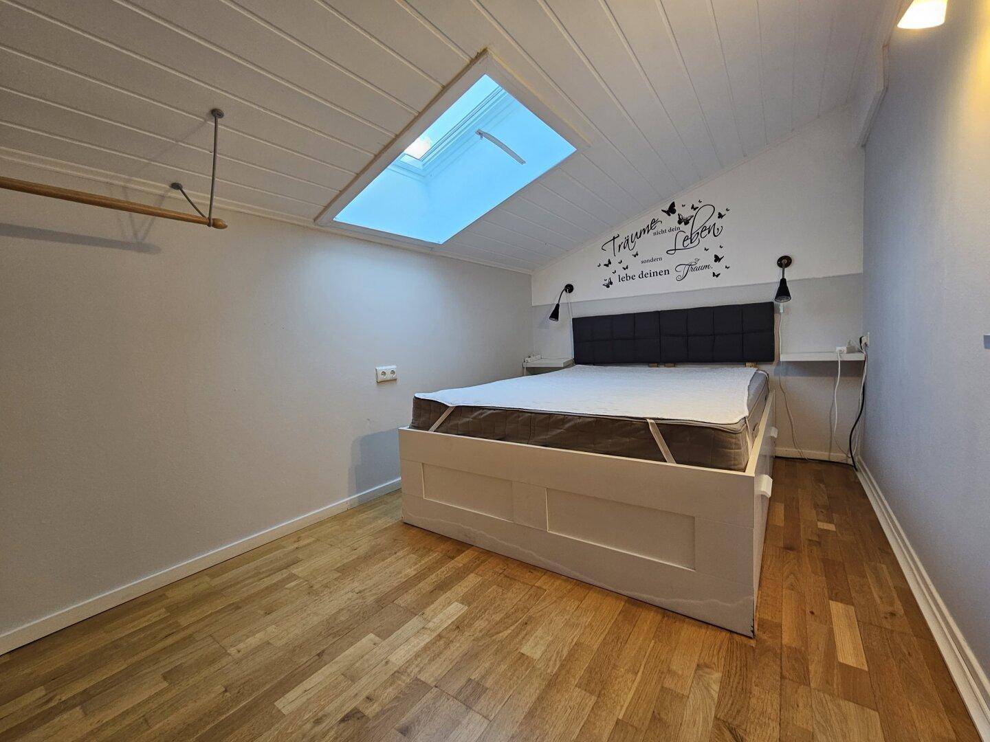 Schlafzimmer mit Doppelbett, Holzboden und Dachfenster für natürliches Licht.