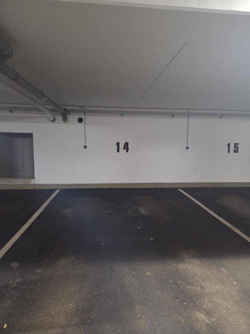 Leere Tiefgarage mit markierten Stellplätzen und Betonwänden.