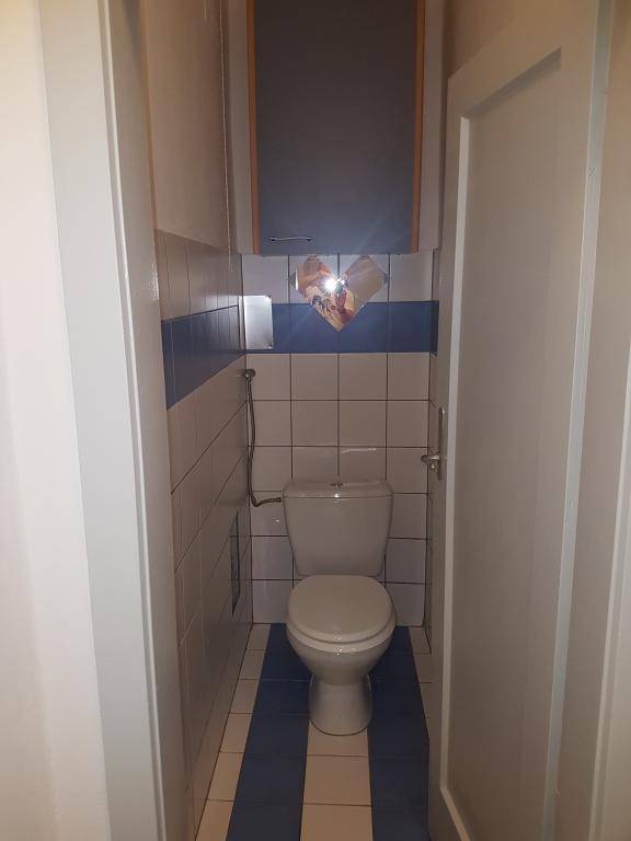 Separate Toilette mit WC, Wandregal und blauen sowie weißen Fliesen.