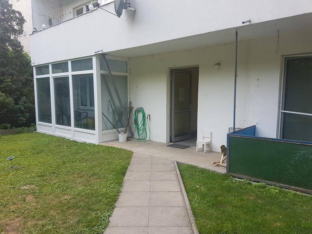 Außenansicht des Erdgeschosses mit Wintergarten, Eingangsbereich und gepflegtem Garten.