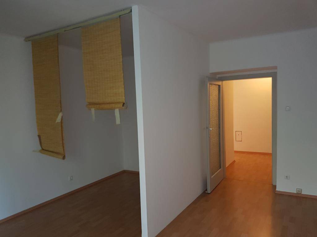 Geräumiger Raum mit Holzparkettboden und Bambusrollos, die eine flexible Raumgestaltung ermöglichen.