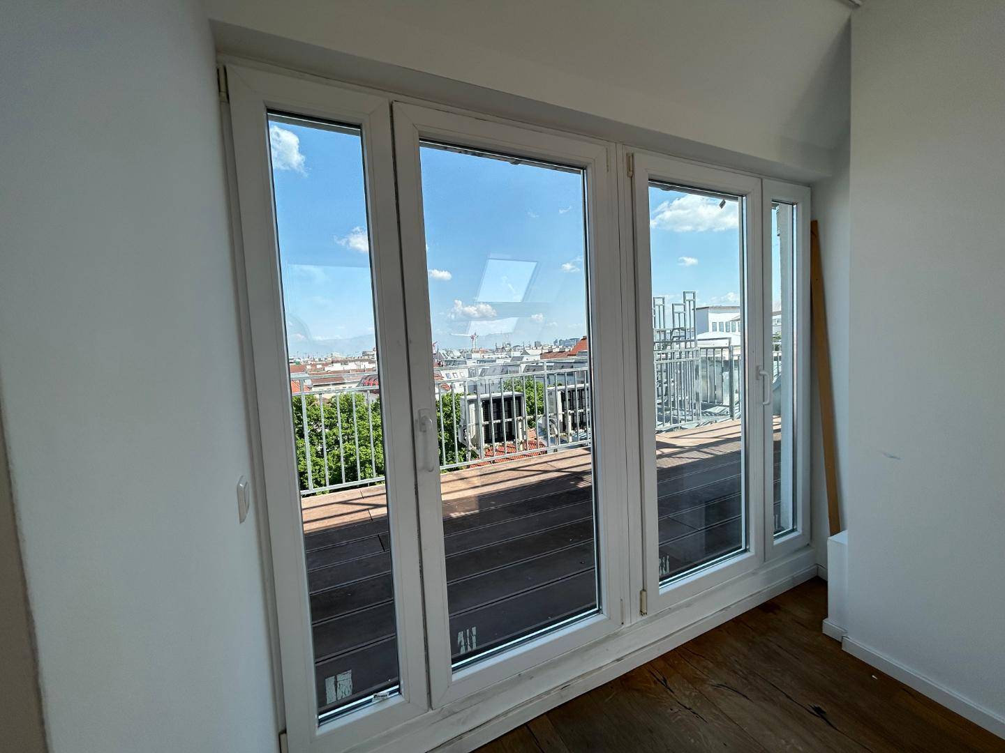 Große Fensterfront mit Holzboden und weitem Blick über die Dächer der Stadt.