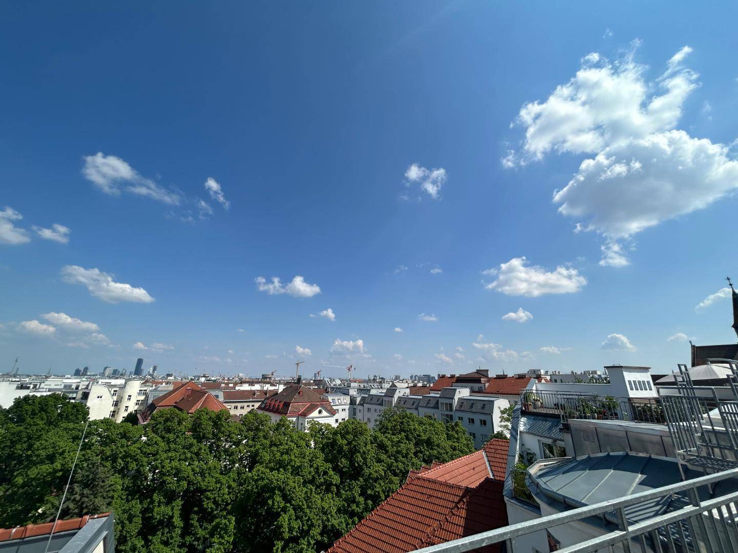 Panoramablick über die städtische Skyline mit roten Dächern und grünen Bäumen.