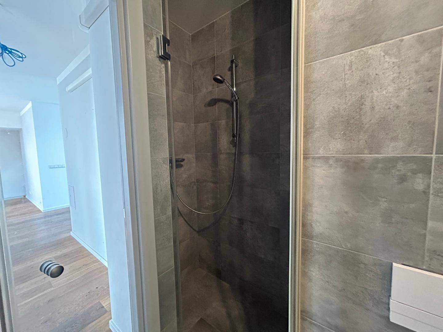 Begehbare Dusche mit modernen grauen Fliesen und einer Duscharmatur.