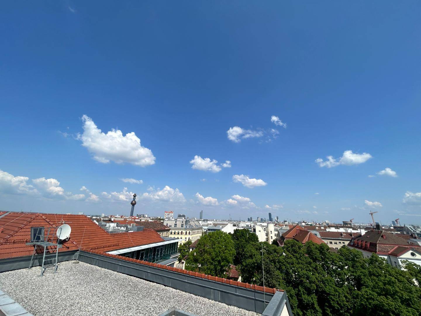 Weiter Blick über die Dächer der Stadt und den Horizont unter blauem Himmel.