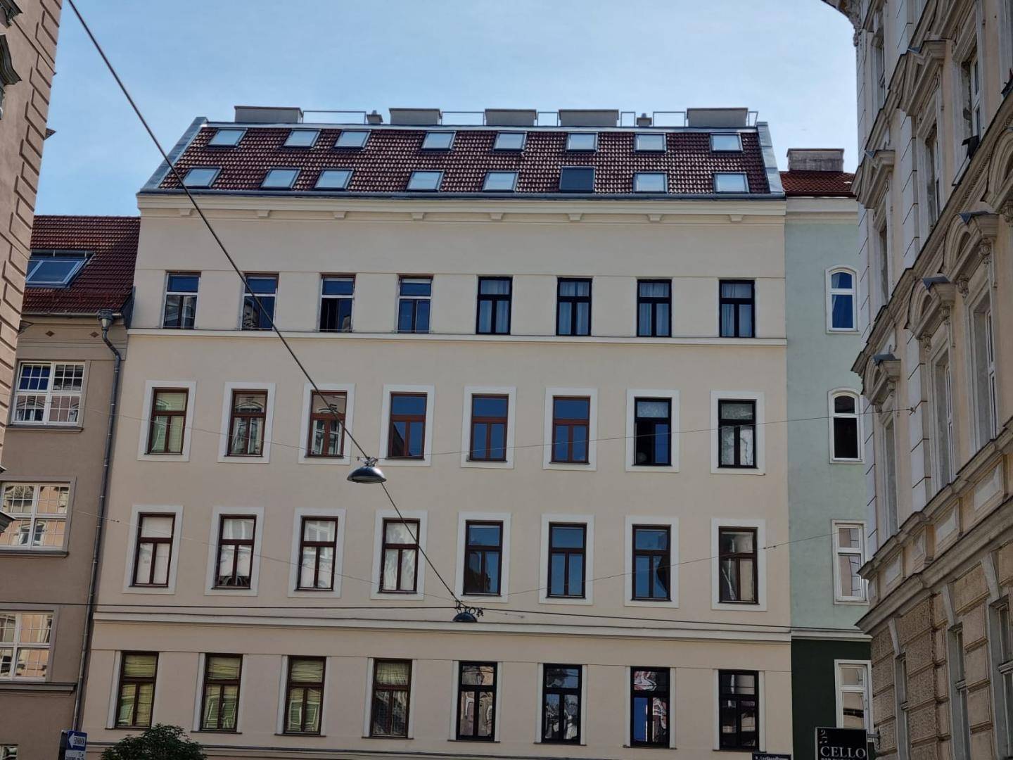 Fassade eines Mehrfamilienhauses mit zahlreichen Fenstern und einem Mansarddach mit Dachfenstern.