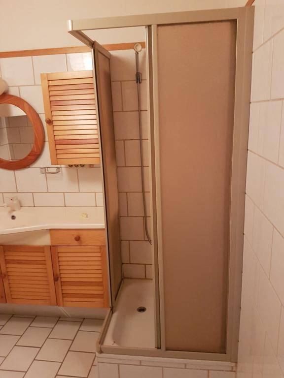 Duschbereich im Badezimmer mit weißen Fliesen und einfacher Duschkabine.