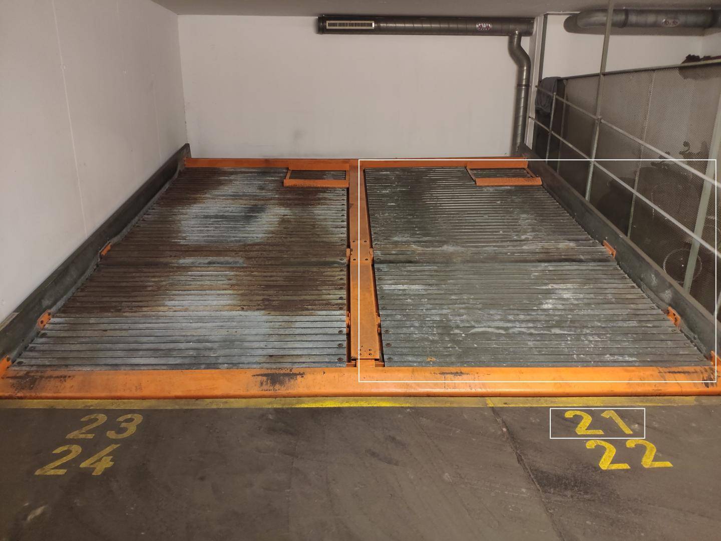 Leere Doppelparker-Stellplätze in einer Tiefgarage mit den Nummern 21, 22, 23 und 24.