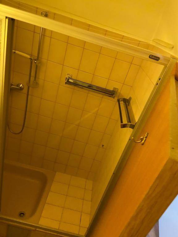 Duschkabine mit beigefarbenen Fliesen und einfacher Duscharmatur in einem Badezimmer.