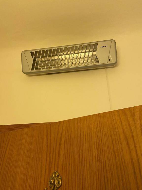 Wandmontiertes Heiz- oder Lüftungsgerät in einem Raum, wahrscheinlich im Badezimmer.