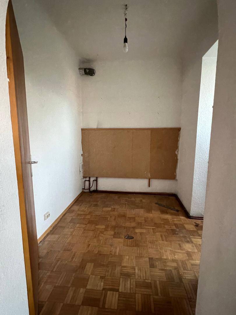 Kleiner, leerer Raum mit Parkettboden und weißen Wänden, ideal als Schlafzimmer oder Büro.