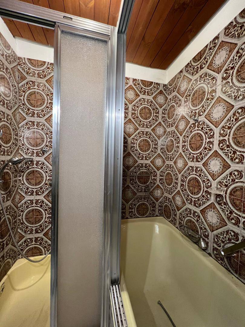 Nahaufnahme des Wannenbereichs in einem Badezimmer mit gemusterten Fliesen und einer Badewanne.