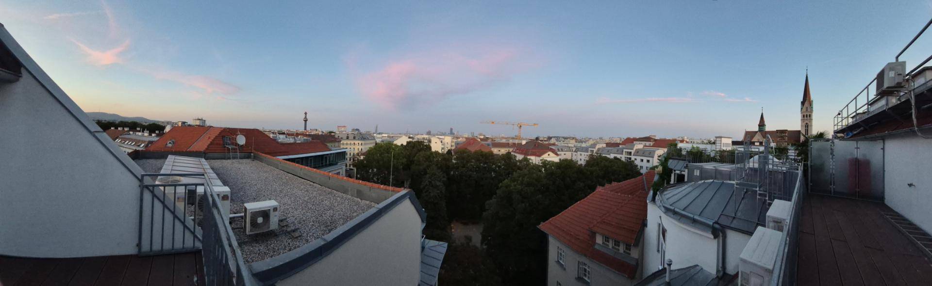 Panoramablick über die Stadt bei Sonnenuntergang mit Dächern und Kirchturm.