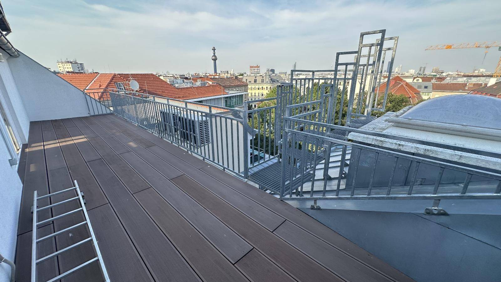Großer Balkon mit Holzboden und Treppe, die zu einer weiteren Ebene führt.