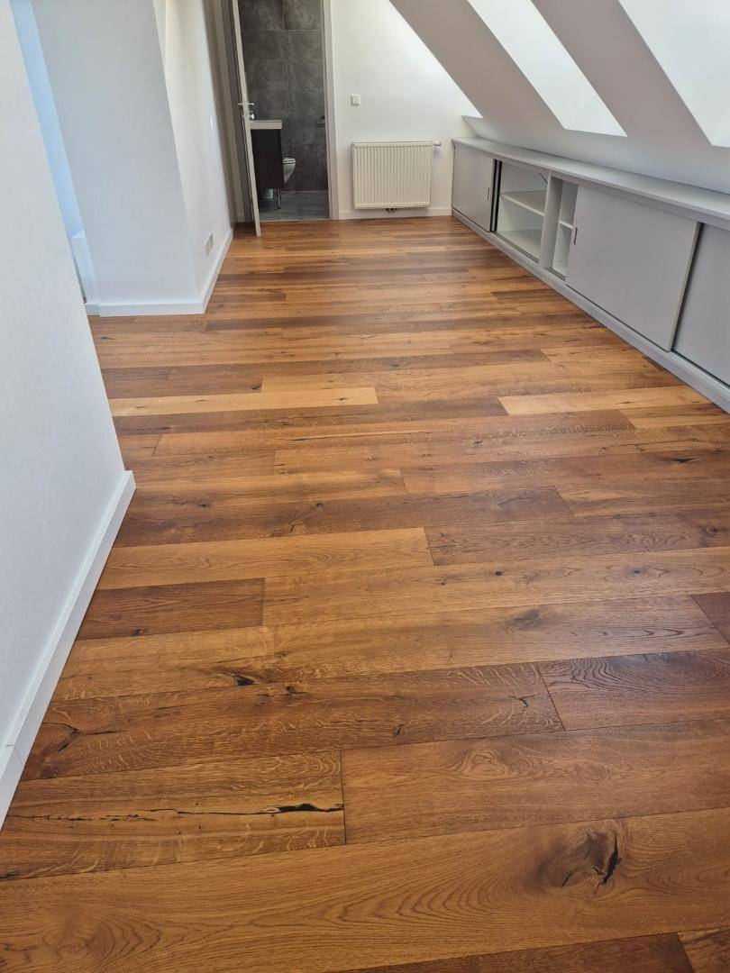 Geräumiges Zimmer im Dachgeschoss mit Holzboden und integrierten Schränken unter der Schräge.