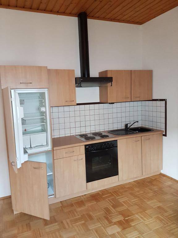 Kompakte Küchenzeile im Dachgeschoss mit Kühlschrank, Herd, Backofen und Dunstabzugshaube.