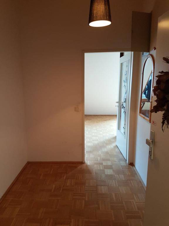 Heller Flur mit Parkettboden und Blick durch eine offene Tür in einen weiteren Raum.