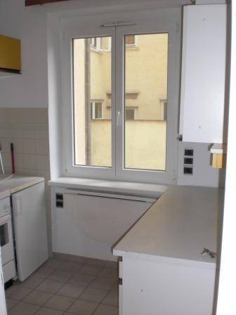 Helle Küche mit Fliesenboden, Fenster und weißen Arbeitsflächen.
