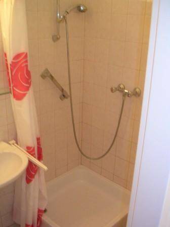 Duschbereich im Badezimmer mit Fliesenwänden und Duschvorhang.