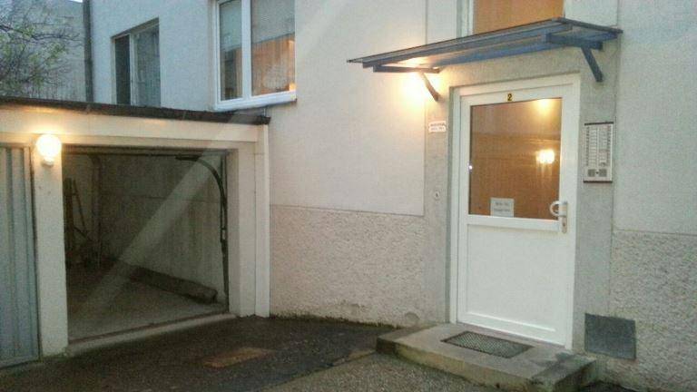 Eingangsbereich im Erdgeschoss mit weißer Haustür, Vordach und angrenzender Garageneinfahrt.