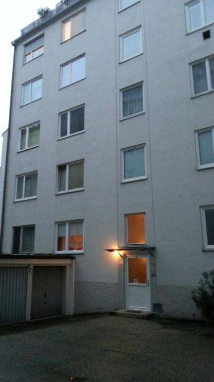 Außenansicht eines Mehrfamilienhauses mit vielen Fenstern, einem Eingangsbereich und einer Garage im Erdgeschoss.