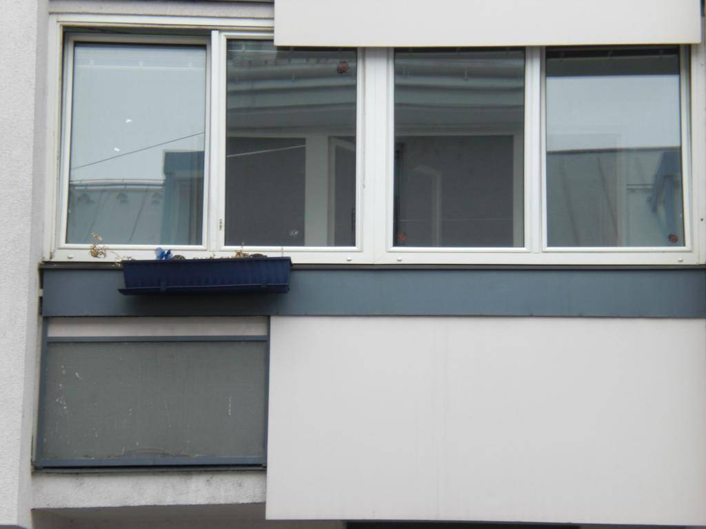 Nahaufnahme der Fensterfront und eines kleinen Balkonbereichs an der Gebäudefassade.