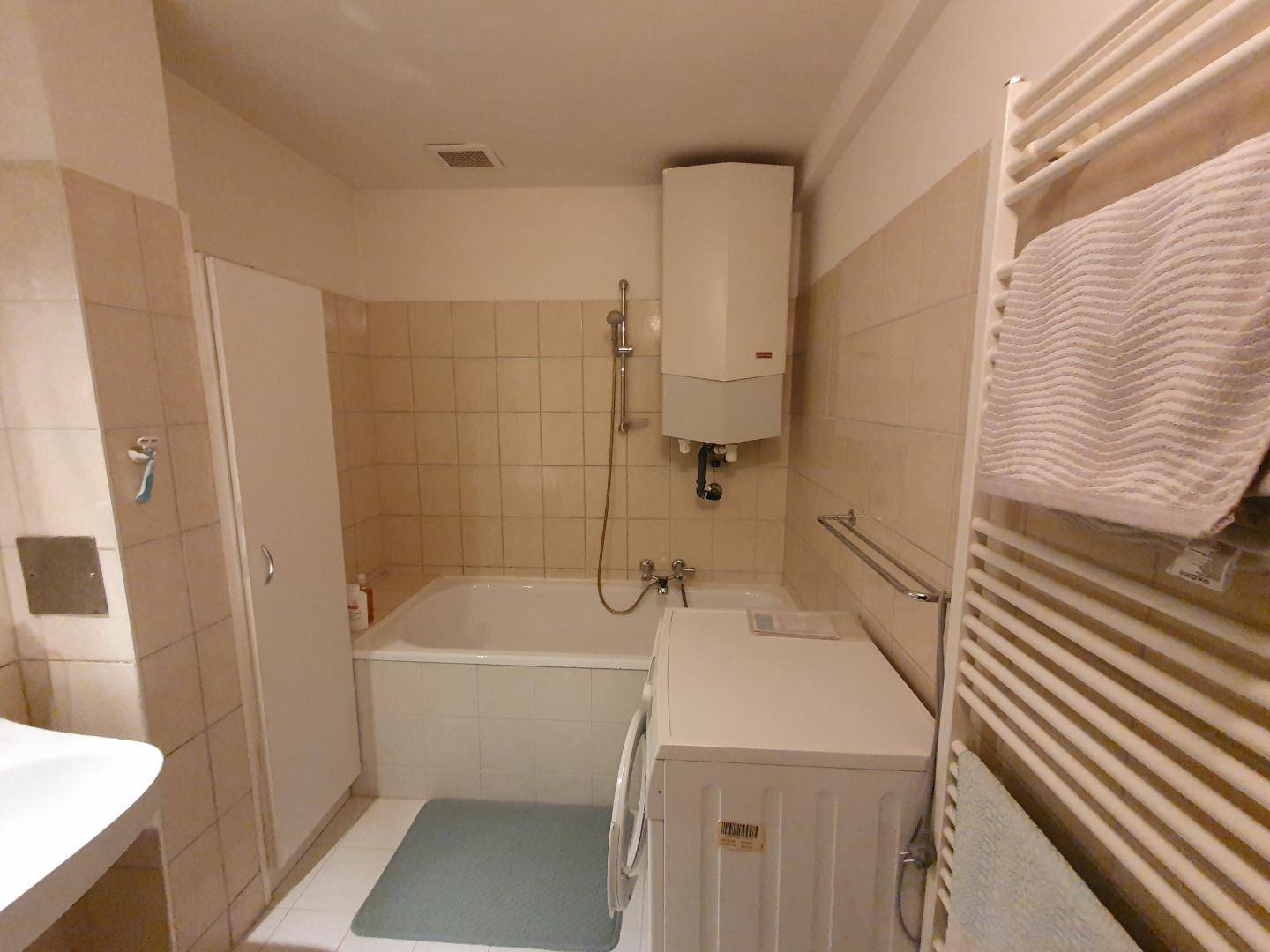 Badezimmer mit Badewanne, Waschmaschine und Heizkörper.