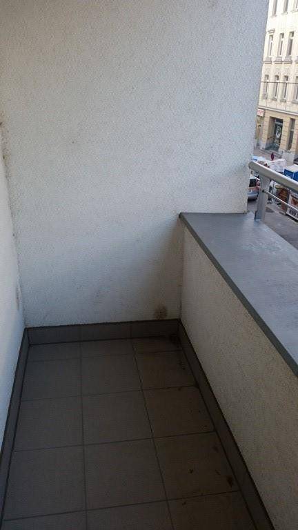 Ecke eines kleinen Balkons mit Fliesenboden und Blick auf die städtische Umgebung.