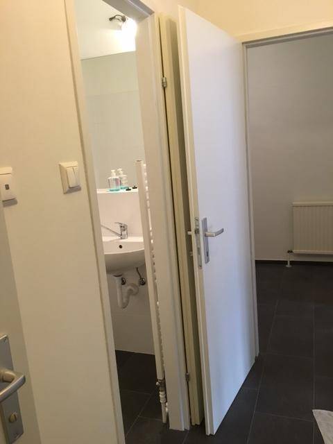 Blick in ein Badezimmer mit Waschbecken, großem Spiegel und weißen Fliesen.