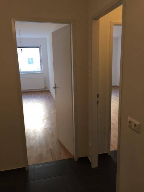 Flur mit Blick in zwei angrenzende Zimmer, eines mit Parkett, das andere gefliest.