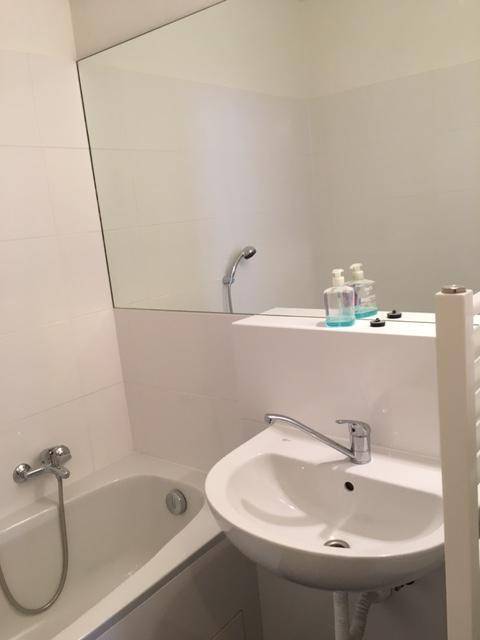 Badezimmer mit Waschbecken, großem Spiegel, Badewanne und einem beheizten Handtuchhalter.