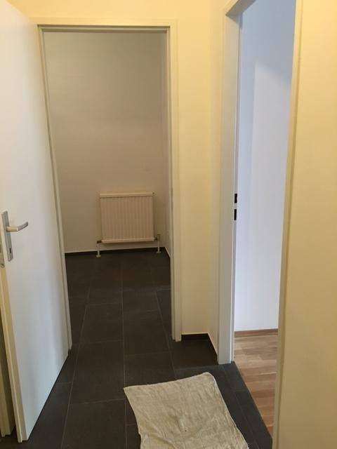 Flur mit dunklen Fliesen, der zu verschiedenen Zimmern der Wohnung führt.