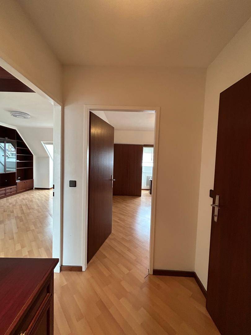 Heller Flur mit Laminatboden und dunklen Holztüren, der zu weiteren Räumen der Wohnung führt.