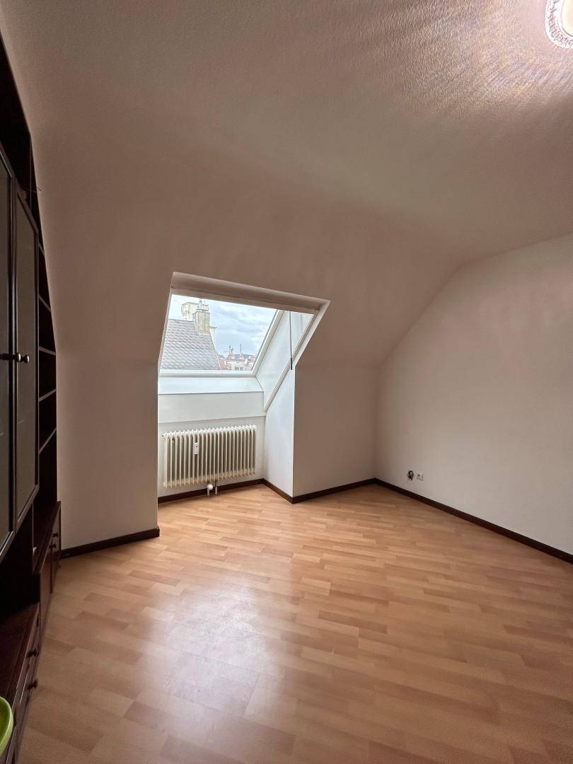 Geräumiger Dachgeschossraum mit Laminatboden, Einbauschrank und großem Dachfenster für viel Tageslicht.