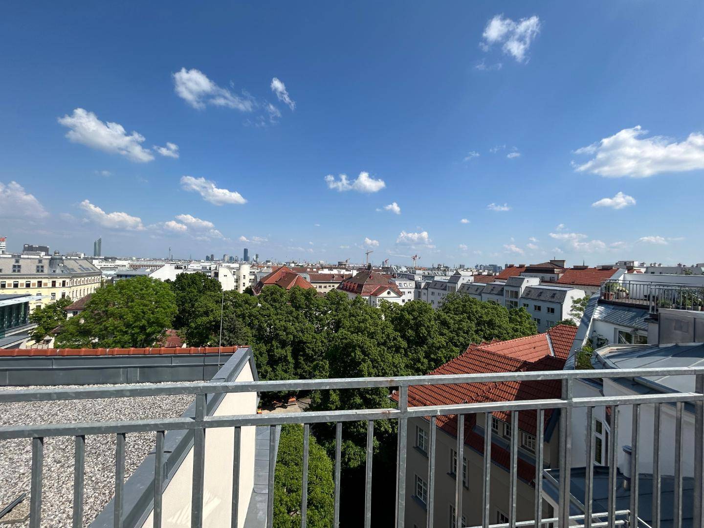 Weitläufiger Blick über die Stadt und Dächer von einer sonnigen Dachterrasse.