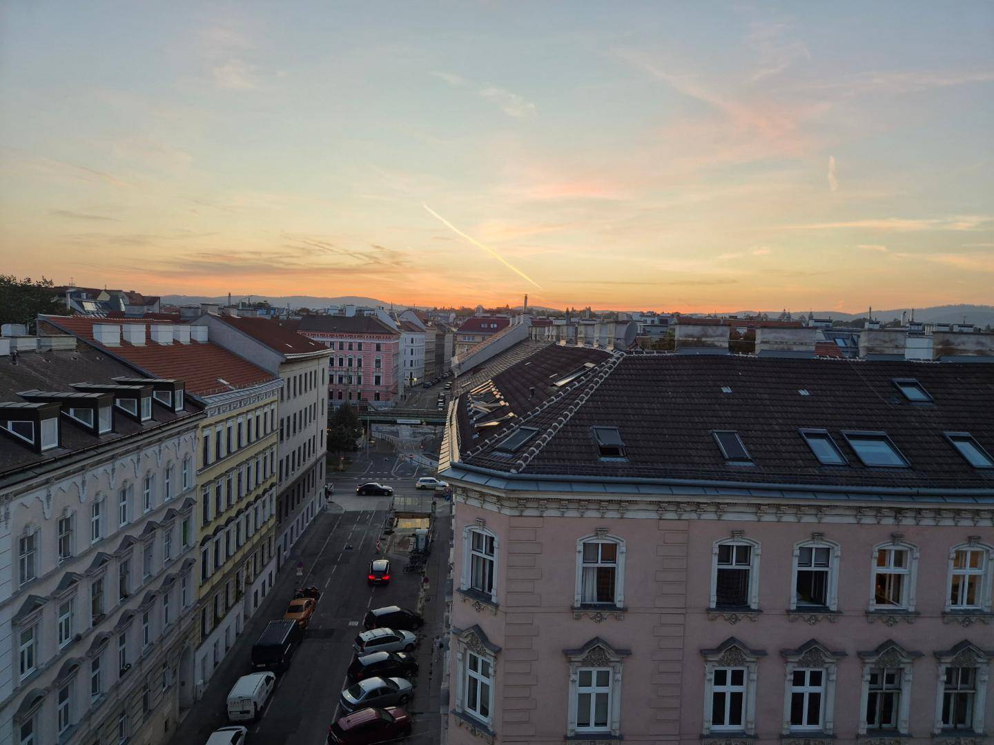 Malerischer Blick über die Stadt bei Sonnenuntergang mit beleuchteten Straßen und Dächern.