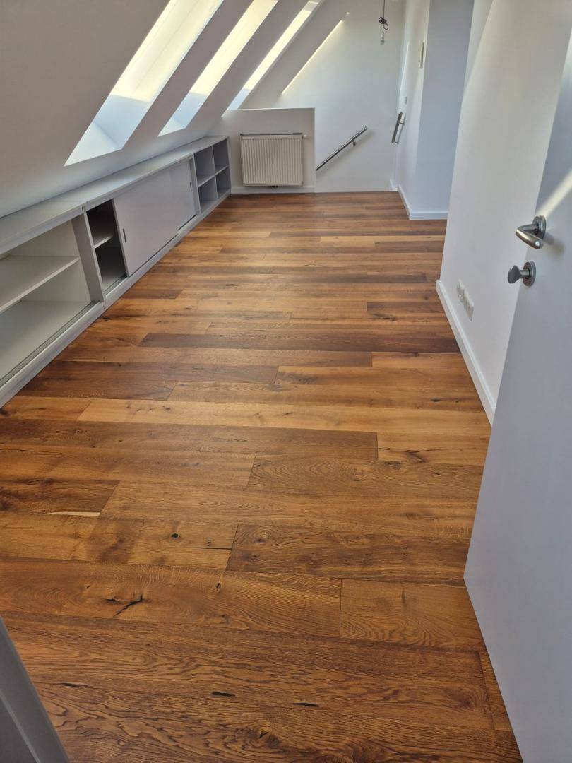 Heller Dachgeschossraum mit Holzboden, Dachschrägen und praktischen Einbauschränken.