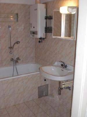 Gefliestes Badezimmer mit Badewanne, Waschbecken, Spiegelschrank und Warmwasserbereiter.