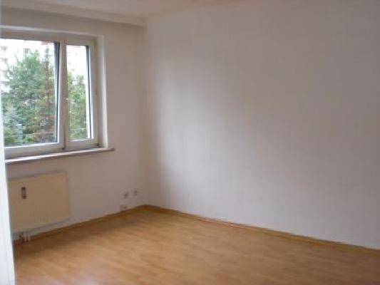 Leeres Zimmer mit weiß gestrichenen Wänden und einem hellen Holzfußboden.