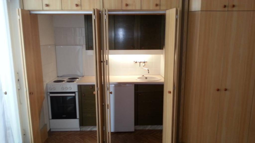 Kompakte Küchenzeile mit Herd, Spüle und Kühlschrank, geschickt in einem Schrank versteckt.