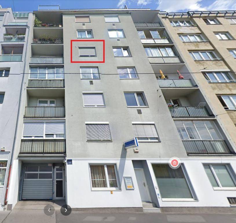 Fassade eines Mehrfamilienhauses mit Balkonen und Fenstern, ein Fenster ist rot markiert.