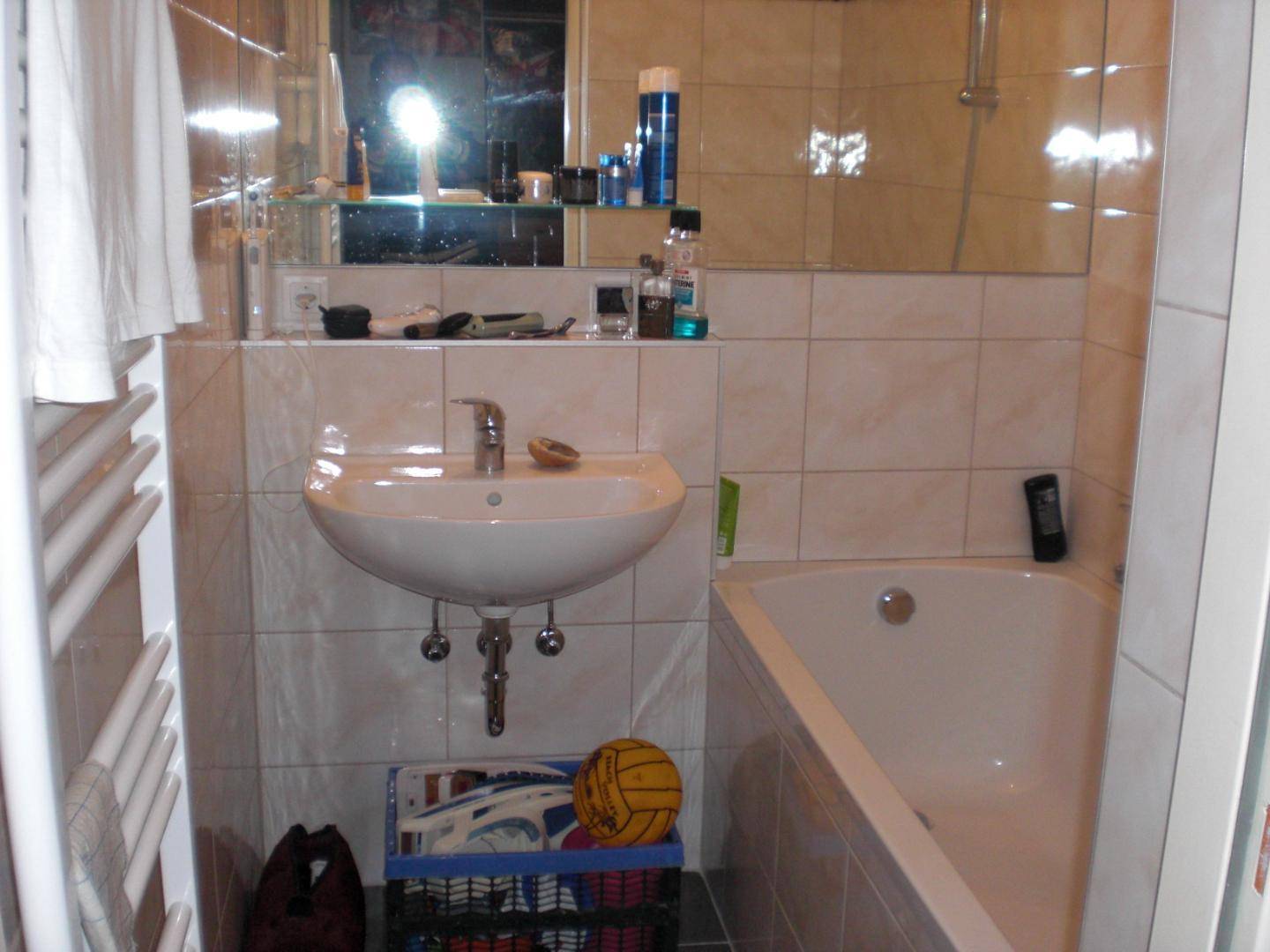 Helles Badezimmer mit Badewanne, Waschbecken und Wandfliesen in neutralen Farbtönen, inklusive Handtuchhalter.