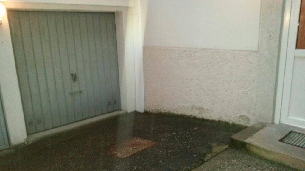 Garagentor und Eingangsbereich eines Wohnhauses mit nasser Oberfläche nach Regen.