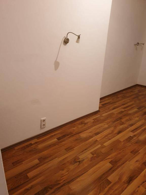 Leerer Raum mit hellem Holzboden und einer Wandleuchte, bereit zur individuellen Gestaltung.