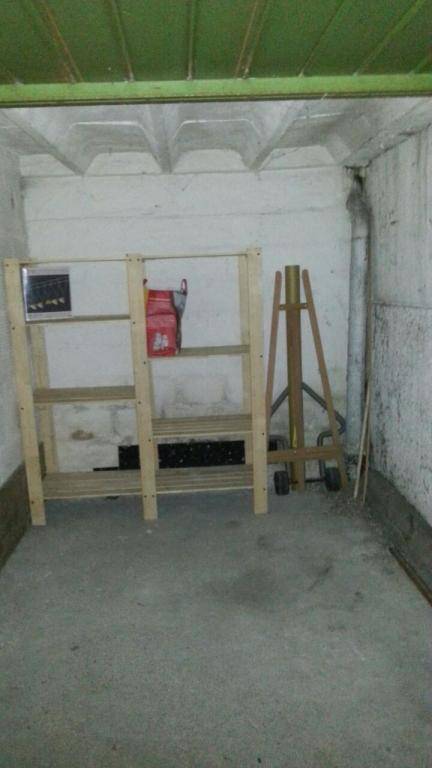 Innenansicht einer Garage oder eines Abstellraums mit Regalen und Betonboden.