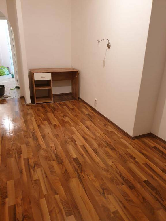 Leerer Raum mit Holzboden und einem kleinen Schreibtisch, ideal für ein Arbeitszimmer.