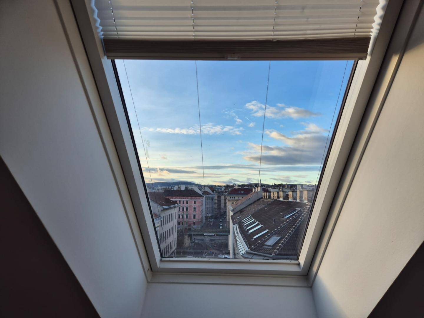 Dachfenster mit Blick auf die Stadt und den Himmel, bringt viel Licht in den Raum.