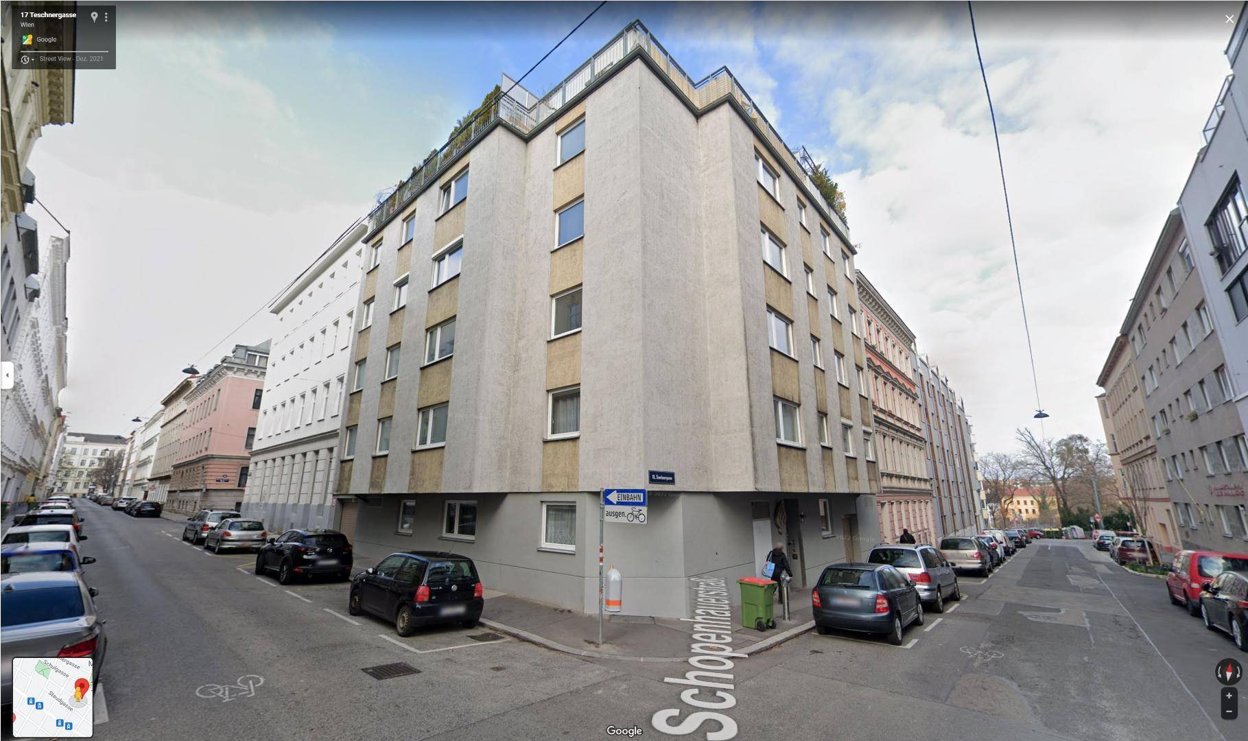 Eckgebäude in einer städtischen Umgebung mit parkenden Autos entlang der Straße.