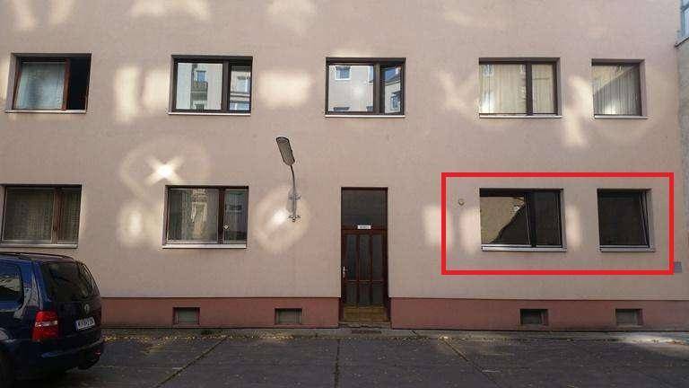 Fassade eines Mehrfamilienhauses mit Fenstern und Eingangsbereich, die Erdgeschossfenster sind markiert.